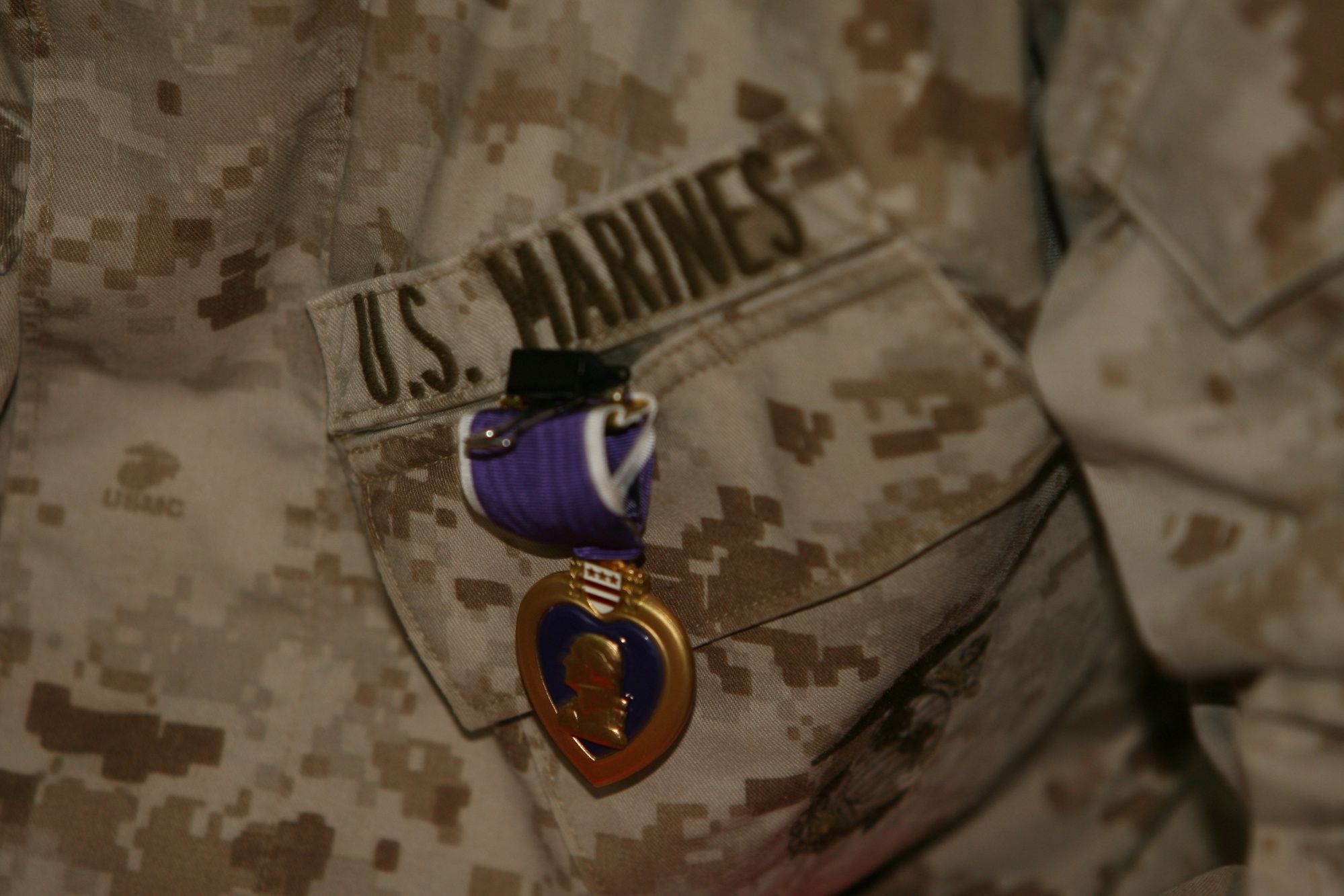 Close-up of a Purple Heart medal pinned to a Marine’s desert camouflage uniform.